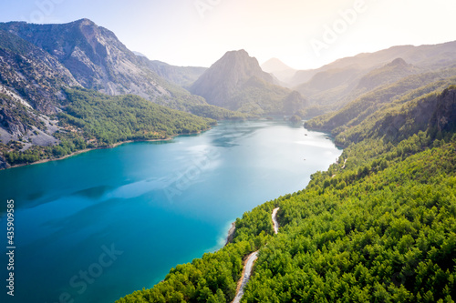 Dam lake in Green Canyon. Beatiful View to Taurus Mountains and turquoise water. Coniferous forest with bright green pine trees and a road stretching into the distance. Manavgat, Turkey