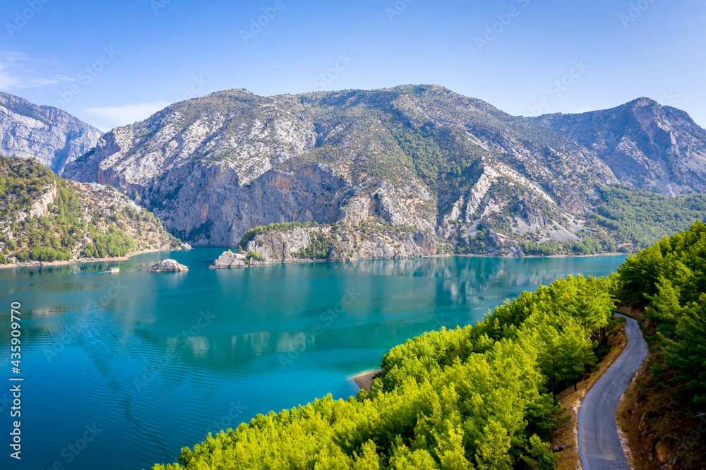 Dam lake in Green Canyon. Beatiful View to Taurus Mountains and turquoise water. Coniferous forest with bright green pine trees and a road stretching into the distance. Manavgat, Turkey