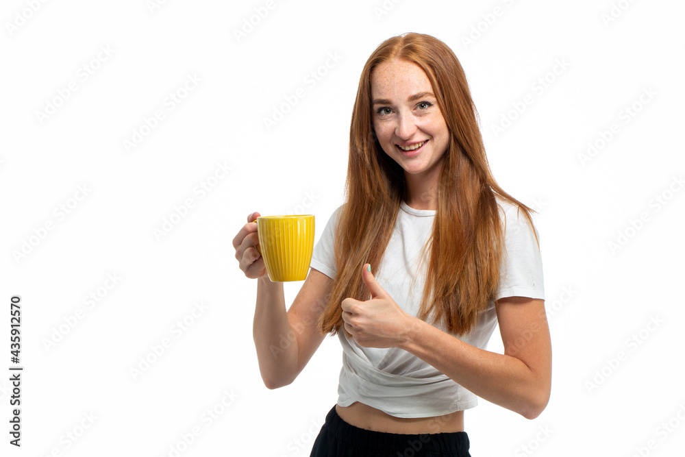 Young beautiful red hair model drinking coffee from yellow mug Young beautiful red hair model drinking coffee from yellow mug