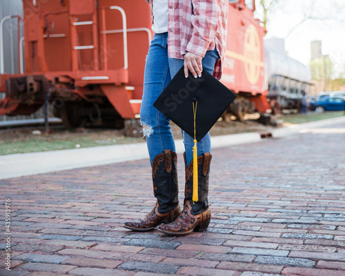 Young female graduate holding her mortar board cap and tassel