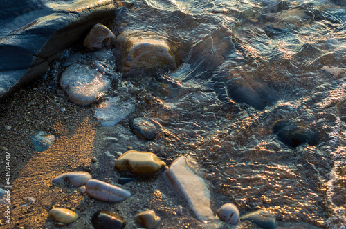 pebble stones on the sea beach, the rolling waves of the sea with foam