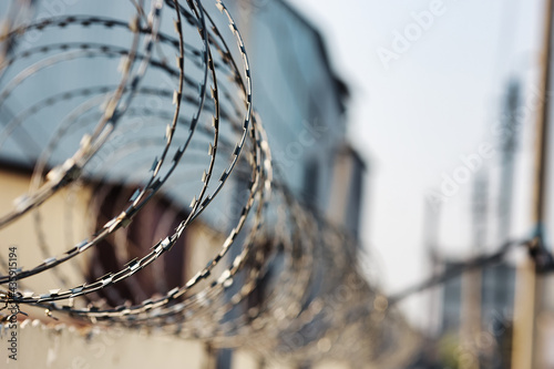 Spirals of barbed wire on a concrete fence. A symbol of incarceration and lack of freedom. Punishment for a crime.
