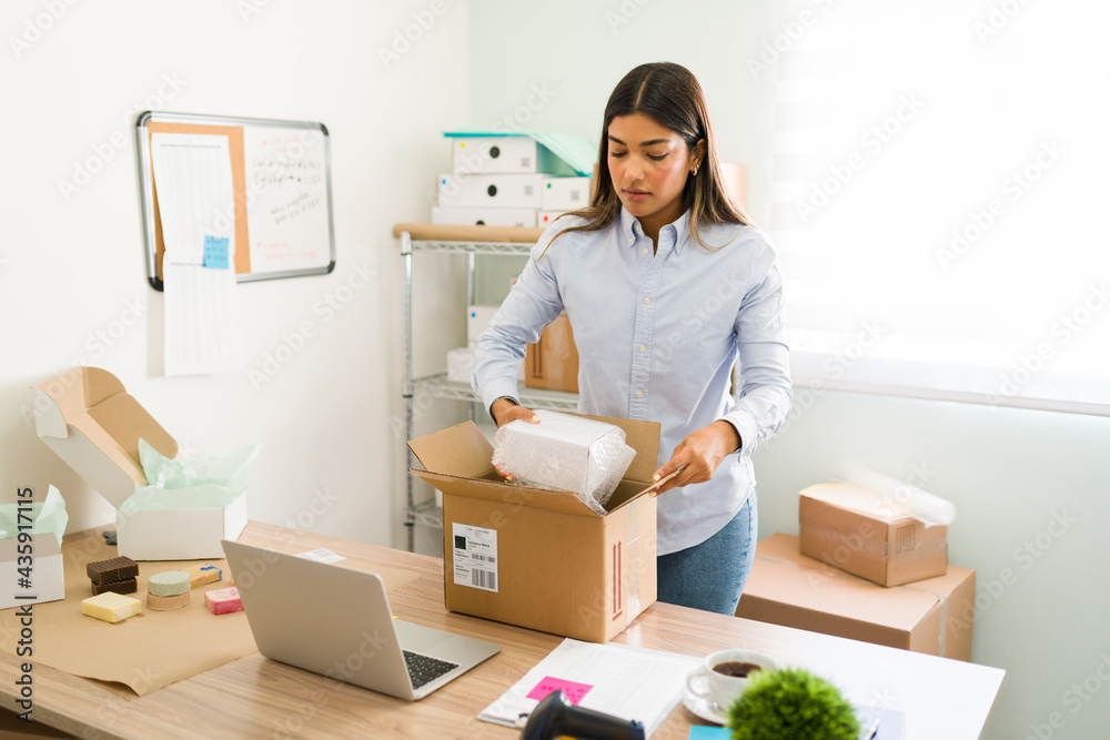 Female entrepreneur putting products on a box