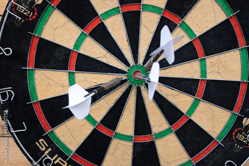 arrows with white feathers stuck in the center of the dart board.