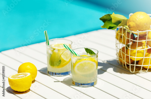 Canvas Print Homemade lemonade in glasses with lemon slice, basket of lemons, drinking straw,