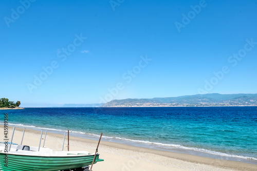 Sandy beach in Messina with views of Calabria and the Messina strait. Tourist season on the mediterranean sea. Sicily. Ionian sea.