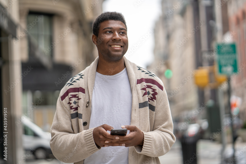 Young black man in city walking street texting on cellphone Young black man in city walking street texting on cellphone