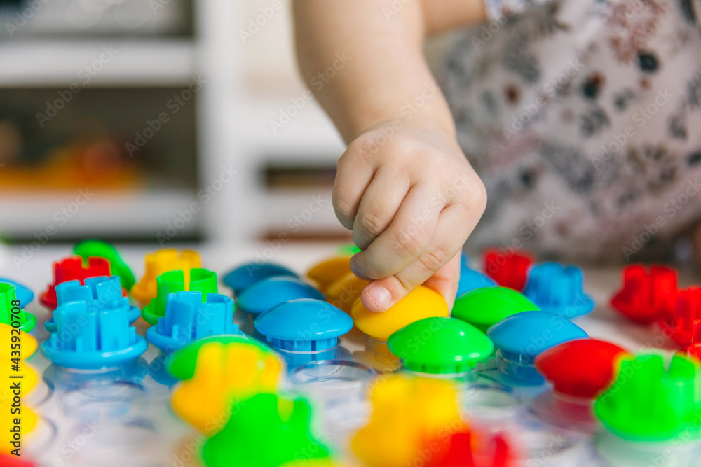 Two-year-old child plays with mosaics, fine motor skills development Two-year-old child plays with mosaics, fine motor skills development