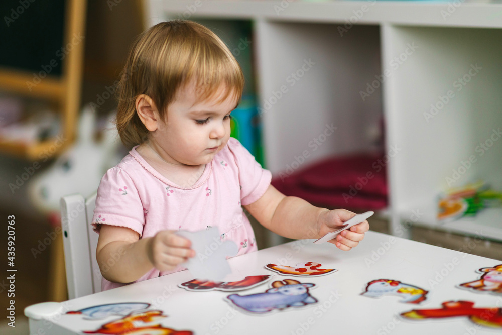 One and a half year old girl collects puzzles. Psychomotor skills and the development of logical thinking One and a half year old girl collects puzzles. Psychomotor skills and the development of logical thinking
