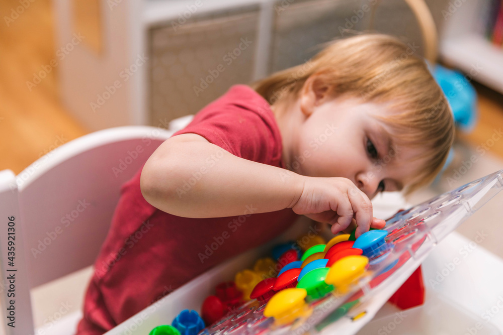 Two-year-old child plays with mosaics, fine motor skills development Two-year-old child plays with mosaics, fine motor skills development