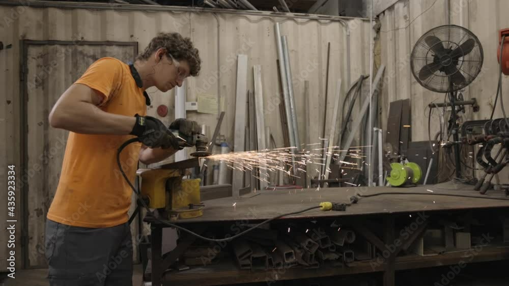 This is a shot of a man in metal fabrication shop grinding angle iron to prepare for welding. This is a shot of a man in metal fabrication shop grinding angle iron to prepare for welding.