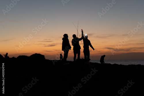 Group of fishermen preparing the rods at sunset in Majorca coast