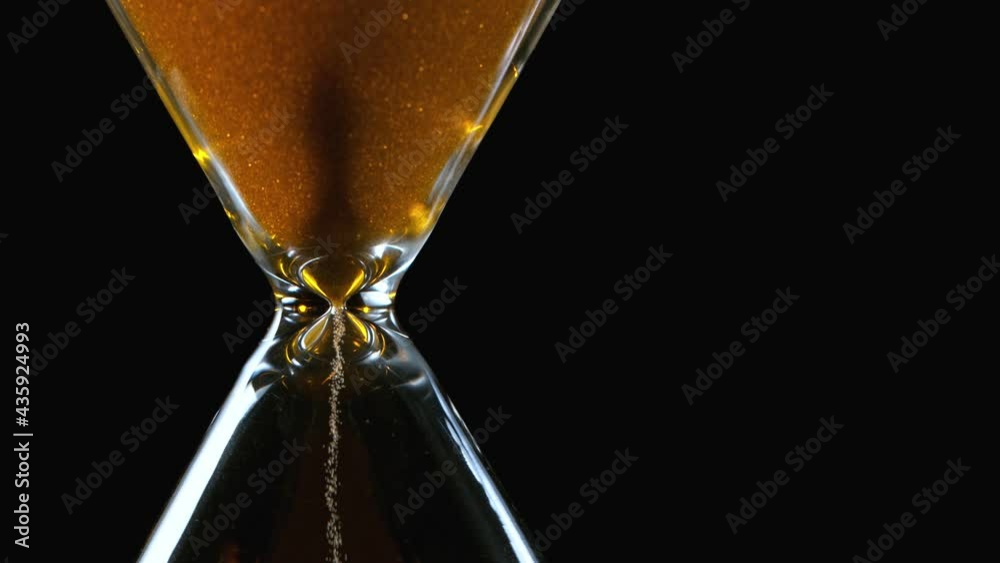 Macro shot of hourglass, the little grains of sand fall from above measuring the time. Super slow motion at 1000 fps.