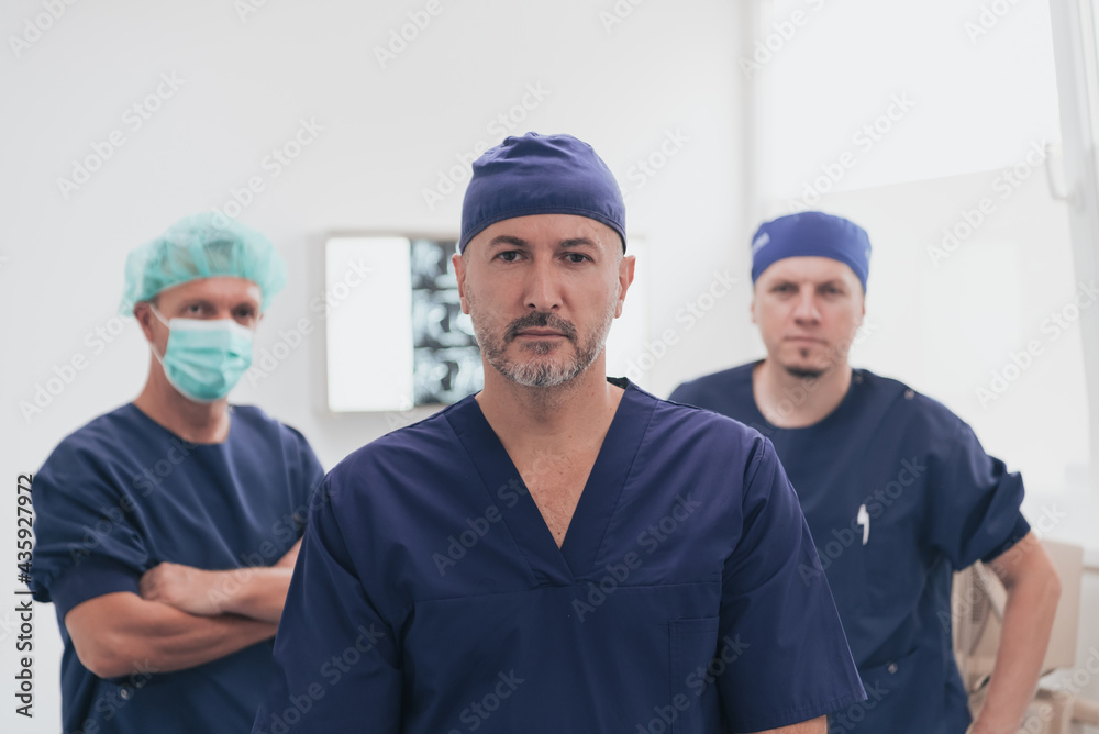 Multiethnic orthopedic doctor in front of his medical team looking at camera wearing face mask Multiethnic orthopedic doctor in front of his medical team looking at camera wearing face mask
