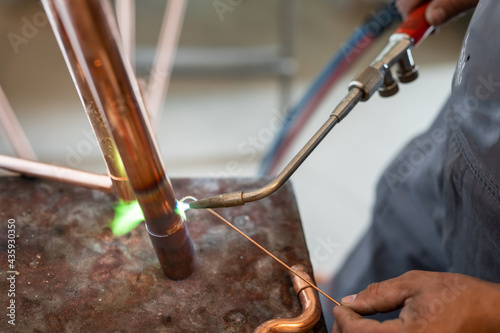 Obraz na plátne Close up on hands of unknown industrial worker plumber with central heating copp
