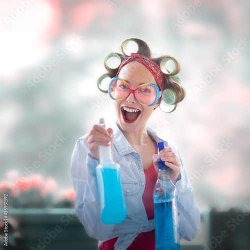 Young woman with curlers in her hair cleans a window with rag and wiper in hand photo