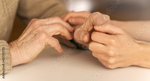 Young woman's hands hold grandmother's hands, an elderly patient. Handshake, caring, trust and support. Medicine, family and healthcare.