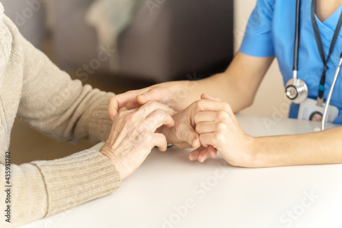 Young woman's hands hold grandmother's hands, an elderly patient. Handshake, caring, trust and support. Medicine, family and healthcare.