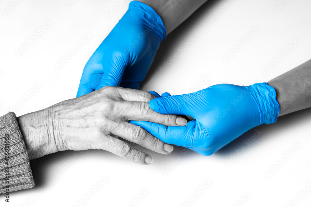 Doctor's hands in a blue gloves holds the hands of an elderly woman, a patient. Handshake, caring, trust and support. Medicine and healthcare. Doctor's hands in a blue gloves holds the hands of an elderly woman, a patient. Handshake, caring, trust and support. Medicine and healthcare.