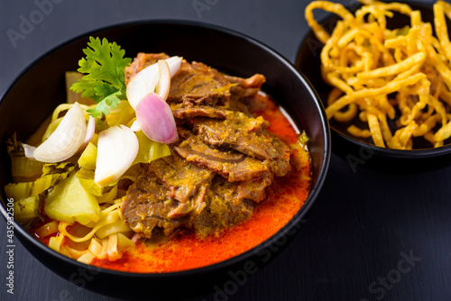 Northern Thai food (Khao soi), Spicy coconut milk curry egg noodles soup with beef in a bowl 