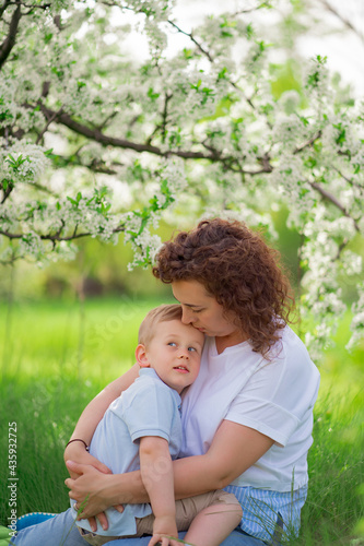 mother sit, holds young son in flowering spring garden. parental love and care © andrey