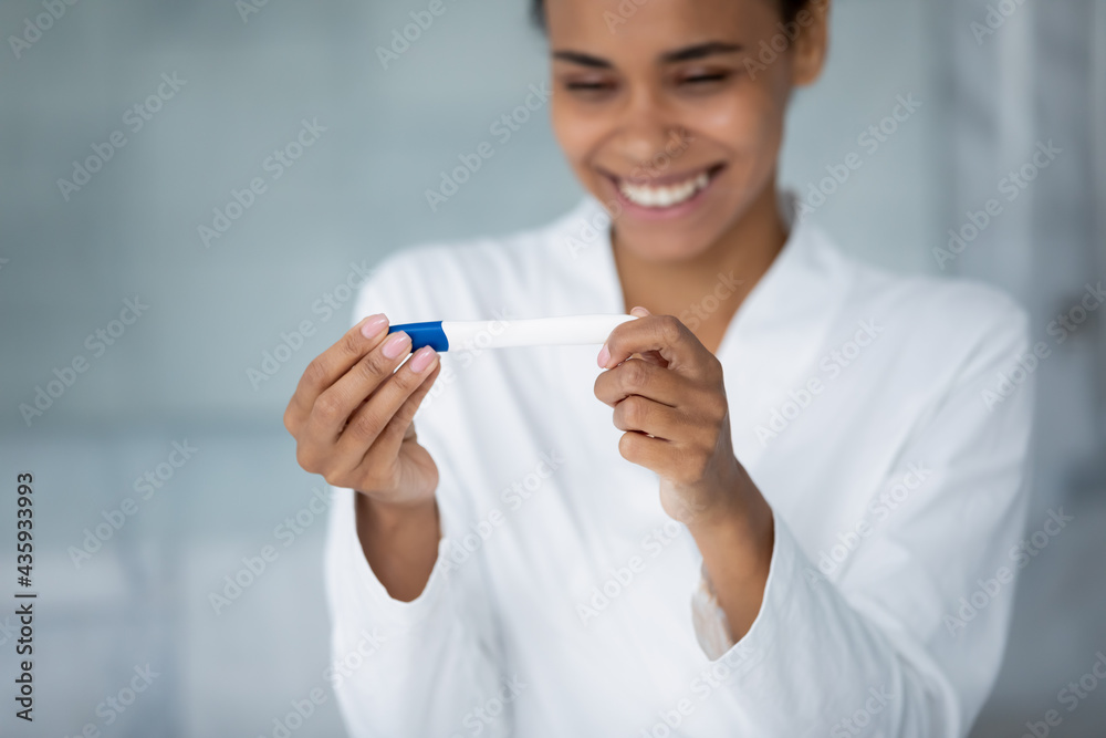 Excited young mixed race pregnant woman happy about positive test result, expecting baby, getting pregnancy confirmation, looking at tester in bathroom, smiling, laughing. Fertility concept. Close up Excited young mixed race pregnant woman happy about positive test result, expecting baby, getting pregnancy confirmation, looking at tester in bathroom, smiling, laughing. Fertility concept. Close up