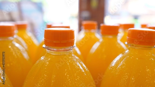 Close up of top parts of orange soda in plastic bottles on a display in a supermarket 