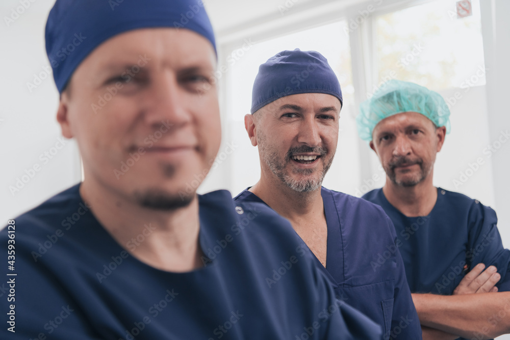 Multiethnic orthopedic doctor in front of his medical team looking at camera wearing face mask 