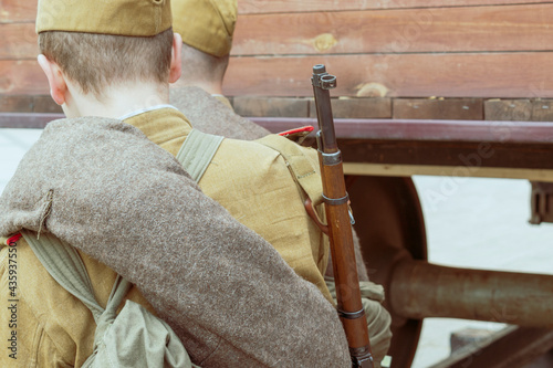 Soldiers of the Red Army during the Second World War stand near a railway carriage. Rifles and military clothing. View from the back. Vintage style. photo