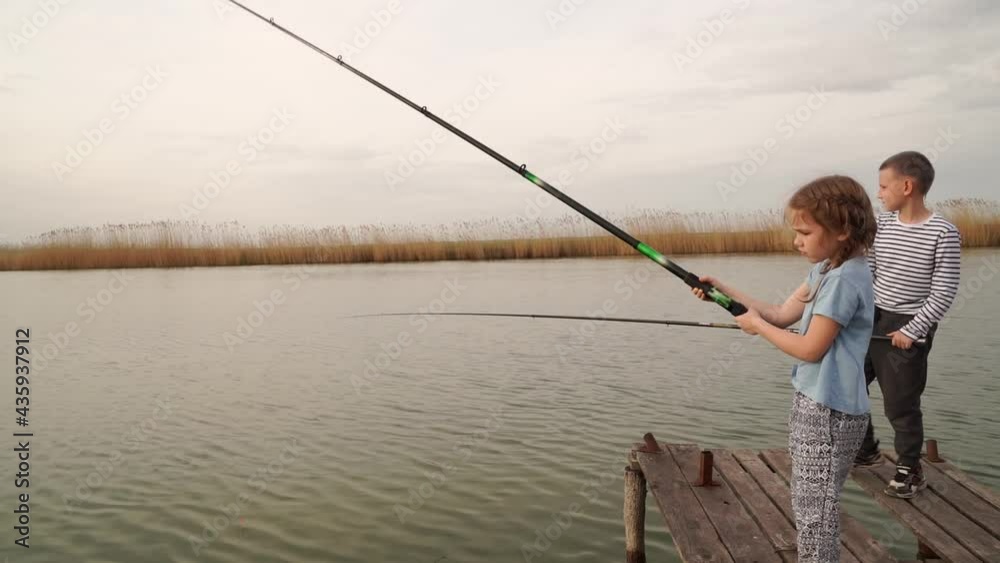 fishermen. little girl and boy fish on a fishing rod standing on a wooden bridge fishermen. little girl and boy fish on a fishing rod standing on a wooden bridge