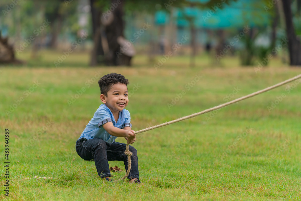 mixed race boy have fun playing rope pulling in park during summer mixed race boy have fun playing rope pulling in park during summer