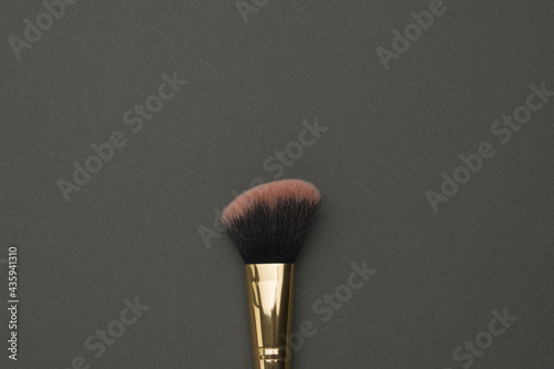Makeup brush with red bristles on a black background.