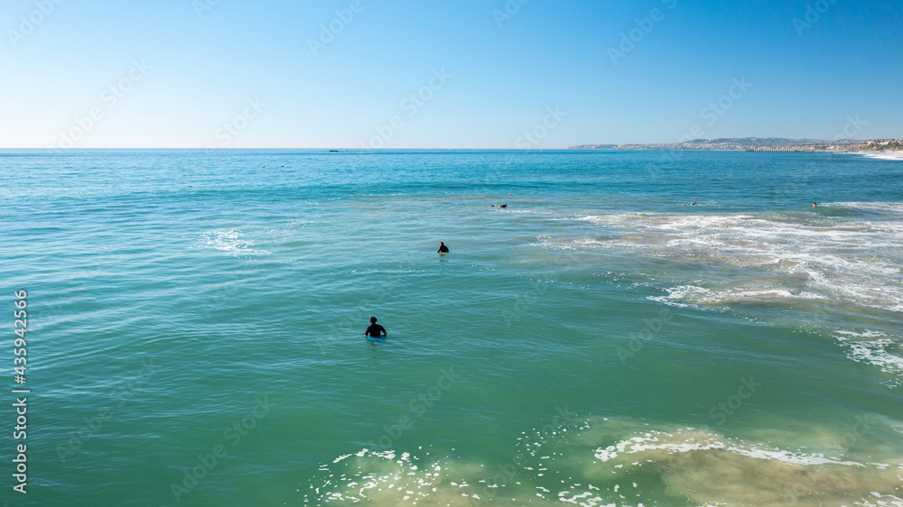 Low Altitude Shot in the Ocean with Surfers Amongst the Waves Low Altitude Shot in the Ocean with Surfers Amongst the Waves