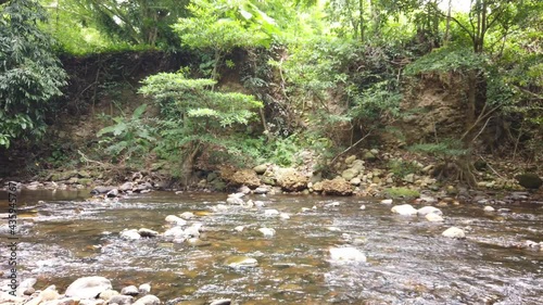 Crystal clear white water flowing downstream over stones and pebbles which make up the riverbed. Wang Takrai stream in Namtok Wang Ta Krai nature park in Nakhon Nayok, Thailand. photo