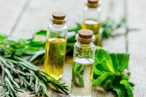 natural cosmetic oil with fresh rosemary and mint on light wooden table background