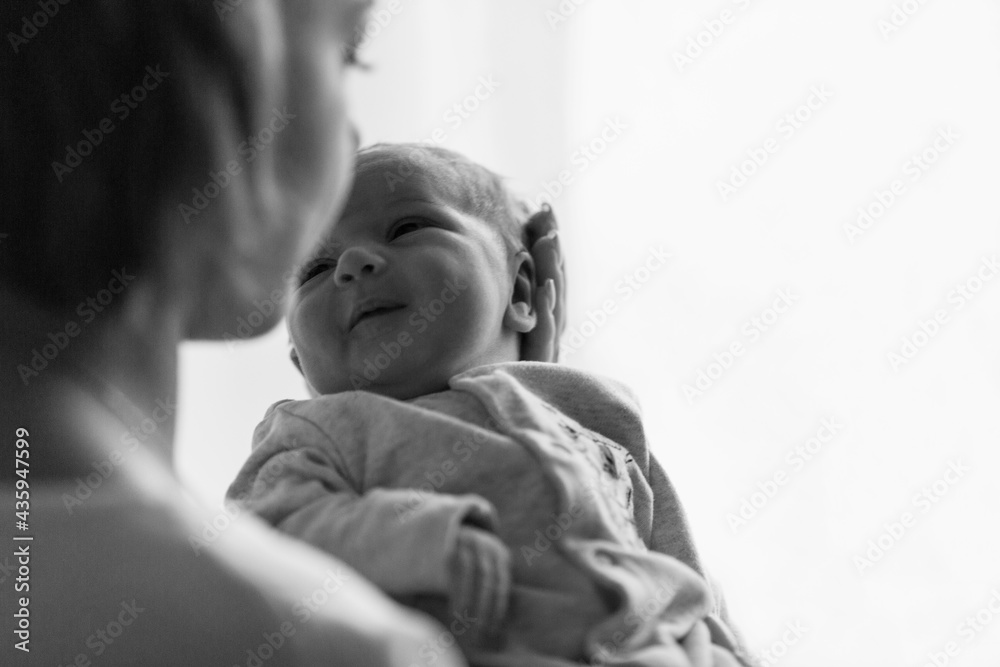 A young mother holds a newborn baby in her arms. Love and tenderness. Black and white photo. Space for text. A young mother holds a newborn baby in her arms. Love and tenderness. Black and white photo. Space for text.