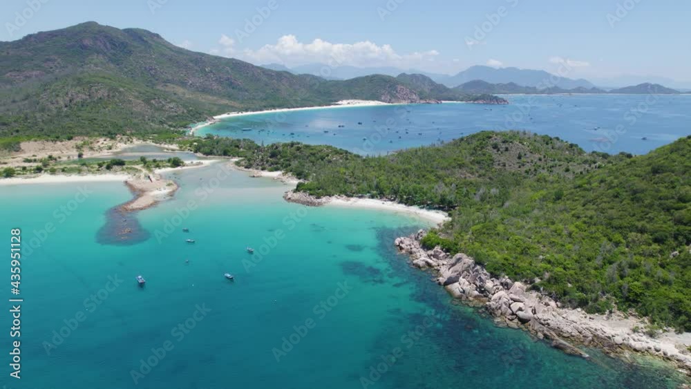 Rotating aerial over crystal clear turquoise waters at Binh Tien Beach surrounded by green cliffs in Vietnam. Rotating aerial over crystal clear turquoise waters at Binh Tien Beach surrounded by green cliffs in Vietnam.