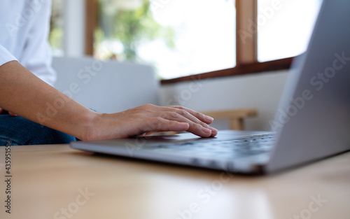 Closeup image of a woman working and touching on laptop touchpad on the table