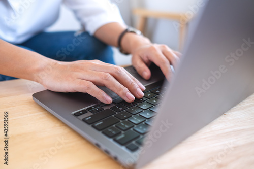 Closeup image of a woman working and typing on laptop computer keyboard on the table