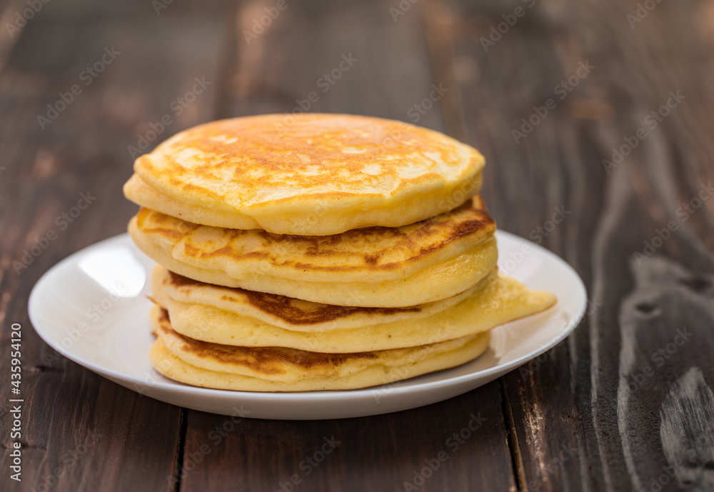 Stack of delicious pancakes in white plate on brown wooden background. It is a homemade breakfast Thick, soft, scented with butter. Stack of delicious pancakes in white plate on brown wooden background. It is a homemade breakfast Thick, soft, scented with butter.
