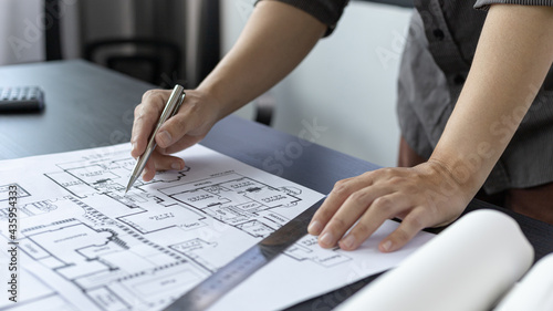 Architectural building design and construction plans with blueprints, Young man was designing a building or architecture with a ruler, pen, pencil, tape measure, architect hat and other equipment.