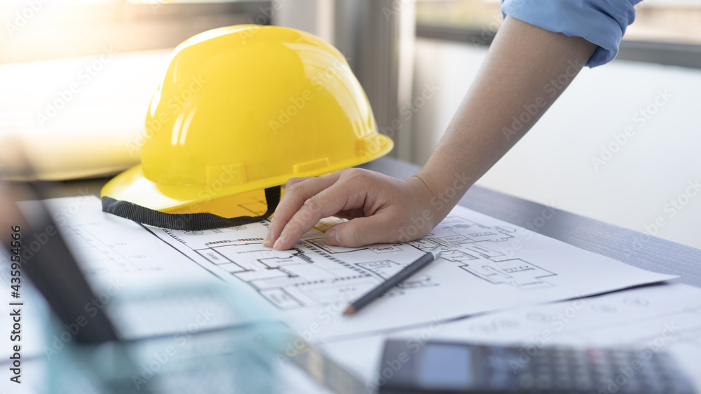 Architectural building design and construction plans with blueprints, Young man was designing a building or architecture with a ruler, pen, pencil, tape measure, architect hat and other equipment.