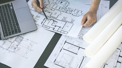 Architectural building design and construction plans with blueprints, Young man was designing a building or architecture with a ruler, pen, pencil, tape measure, architect hat and other equipment.