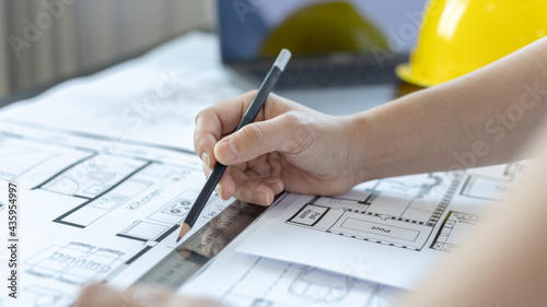 Engineer and Architect concept, Man uses a ruler to measure the floor plan on the blueprint, Building architecture design work, Construction design project under environmental conservation conditions.