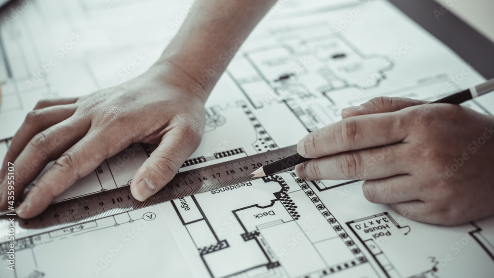 Engineer and Architect concept, Man uses a ruler to measure the floor plan on the blueprint, Building architecture design work, Construction design project under environmental conservation conditions. Engineer and Architect concept, Man uses a ruler to measure the floor plan on the blueprint, Building architecture design work, Construction design project under environmental conservation conditions.