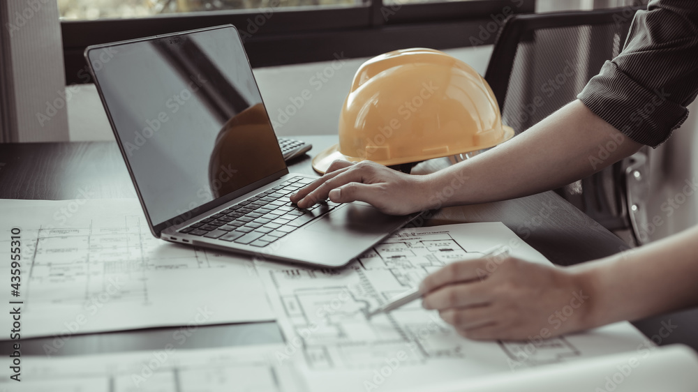 Young man with a laptop plotting a system of building structures in ...