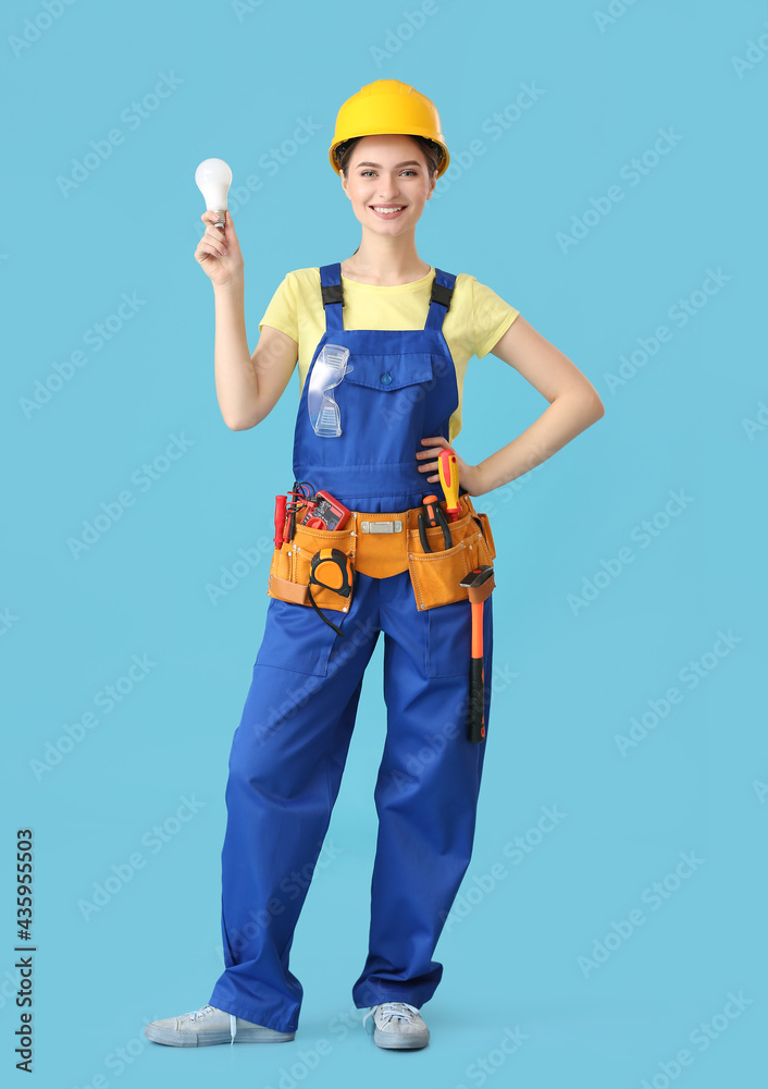 Beautiful female electrician with light bulb on color background Beautiful female electrician with light bulb on color background