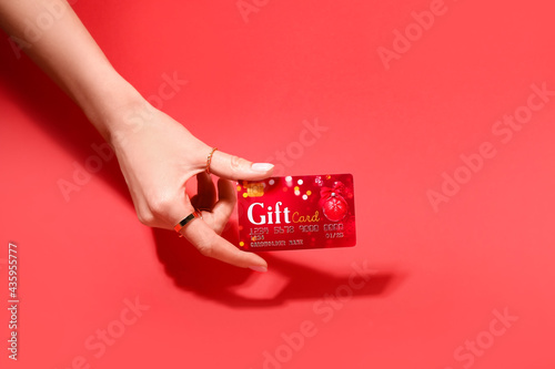 Female hand and gift card on color background photo