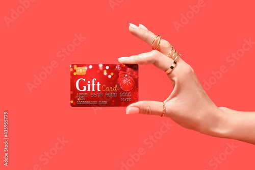 Female hand and gift card on color background photo