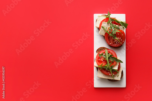 Tasty bruschettas with tomato and tofu cheese on color background